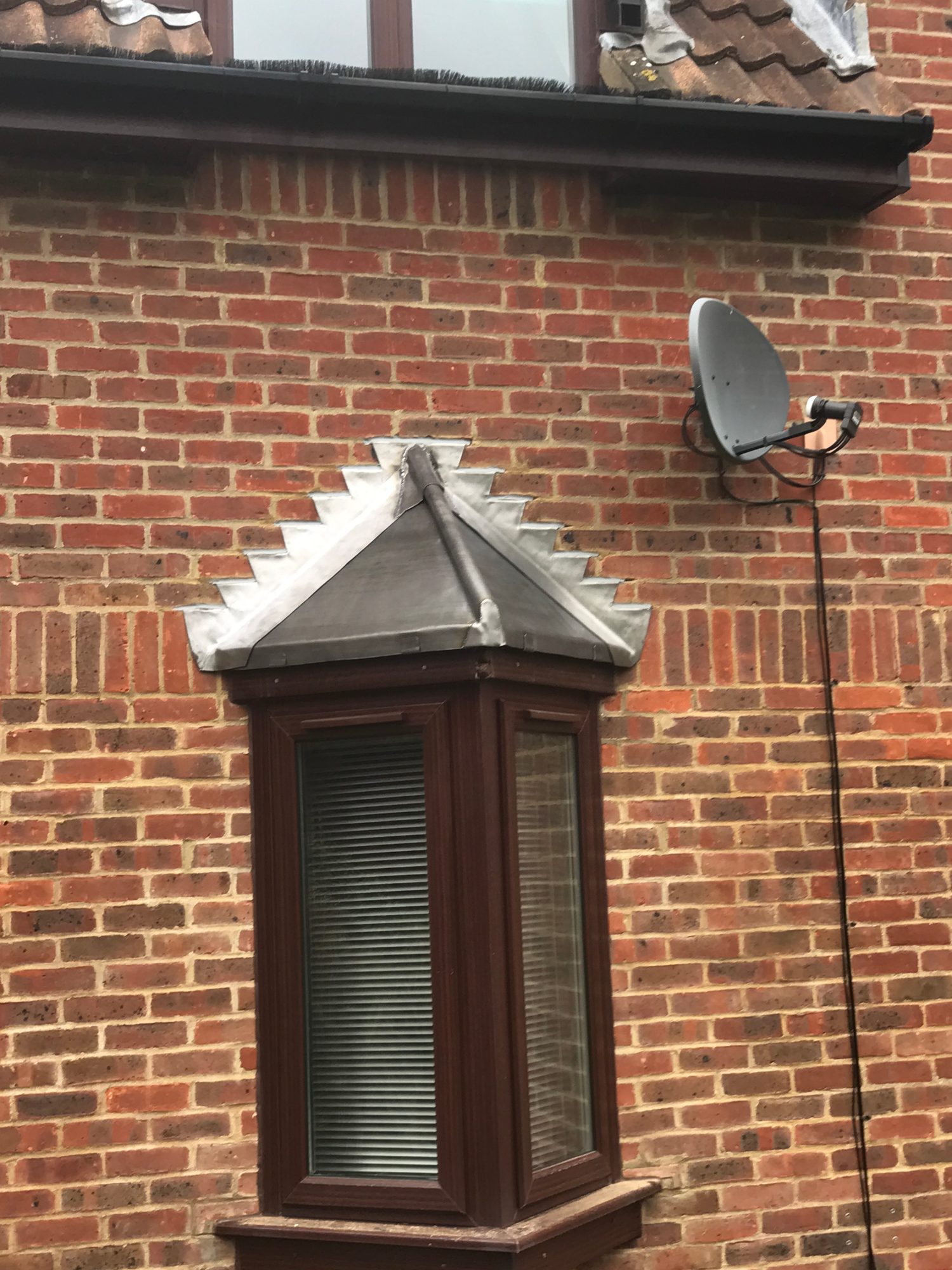 Completed bay window roof with newly installed lead covering and stepped lead flashing against the brick wall