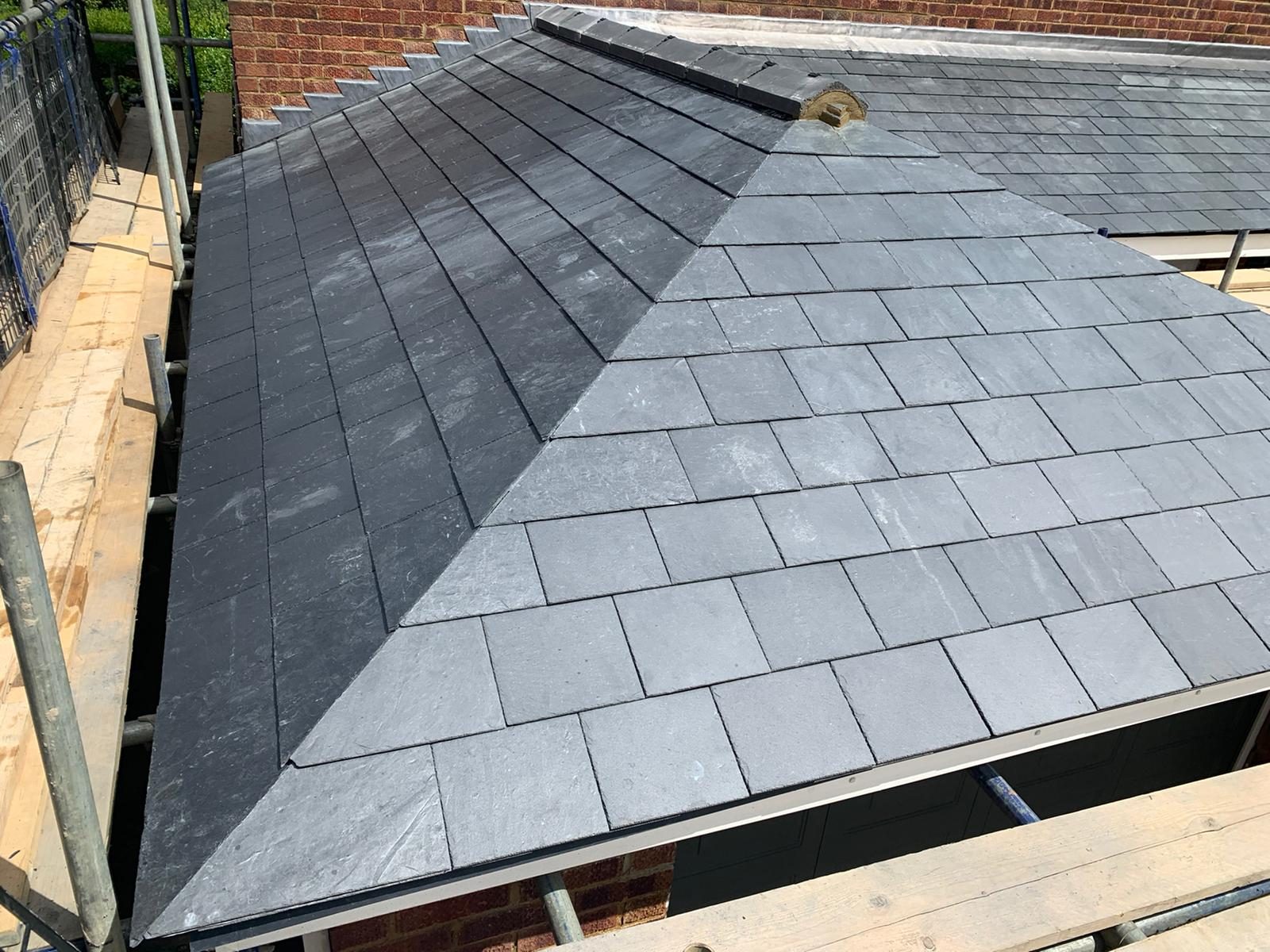 Detailed view of the slate roof showing consistent tile courses, the finished mitred hip running down the roof slope and leadwork along the upper junction