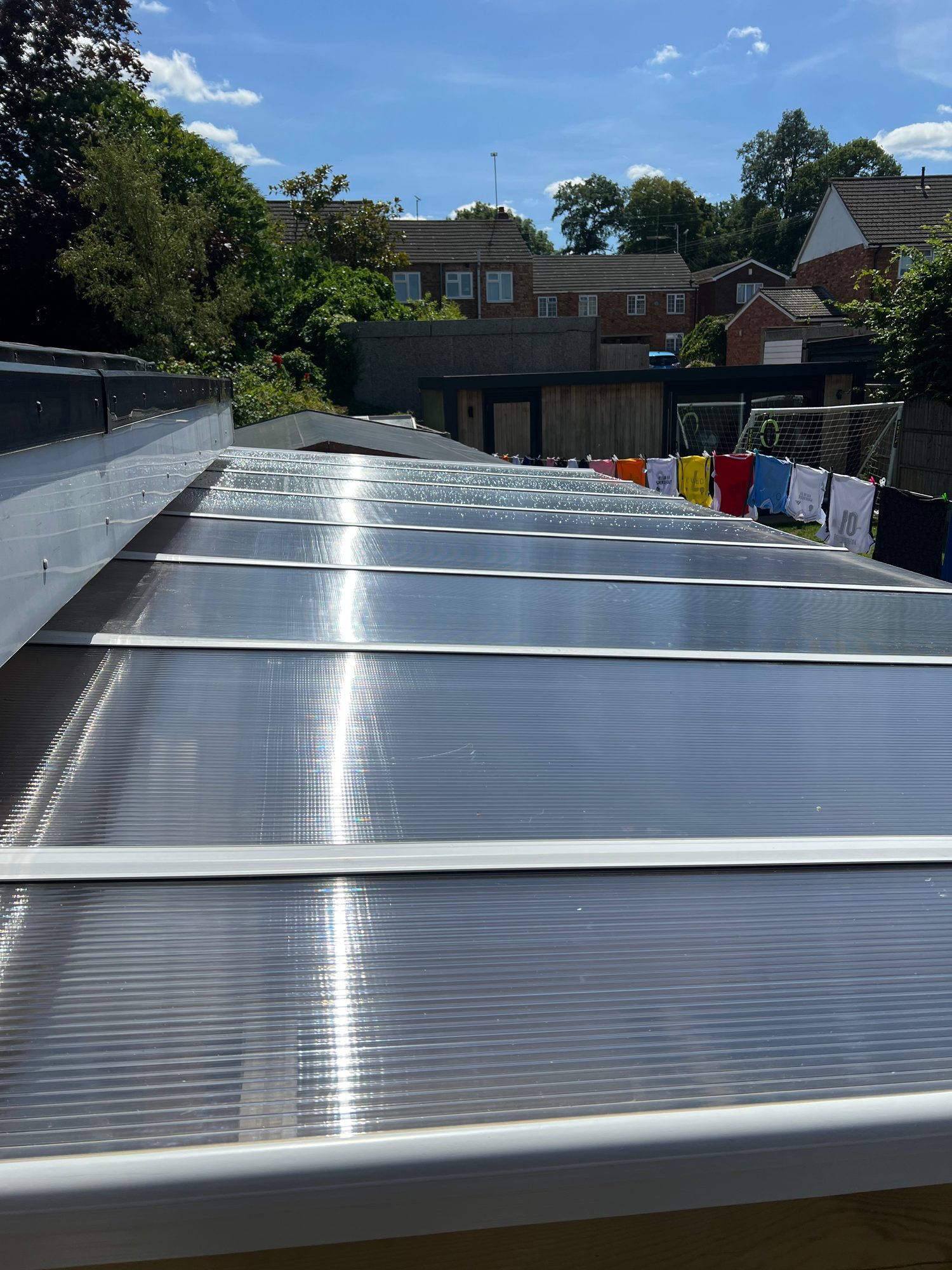 Close view of the completed garden shelter roof with multiple translucent panels secured across the timber frame