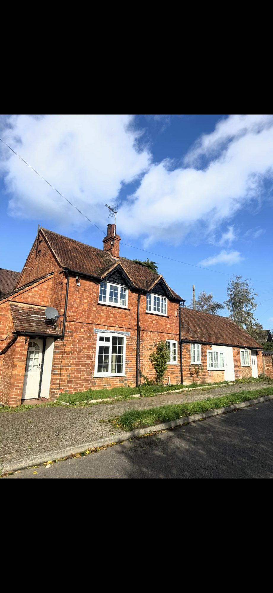 Main brick house and adjoining building with weathered roof tiles, chimney and projecting window gables