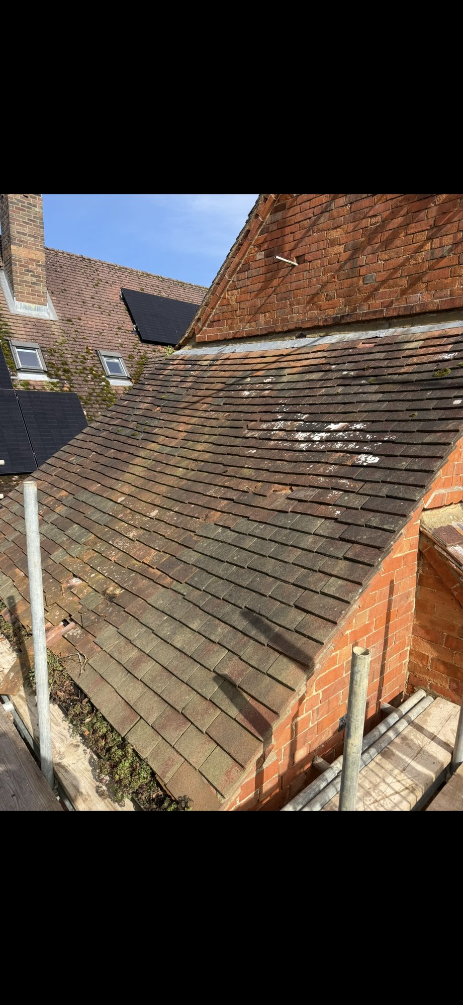 Lower tiled roof showing heavy weathering, discolouration, moss growth and surface deposits