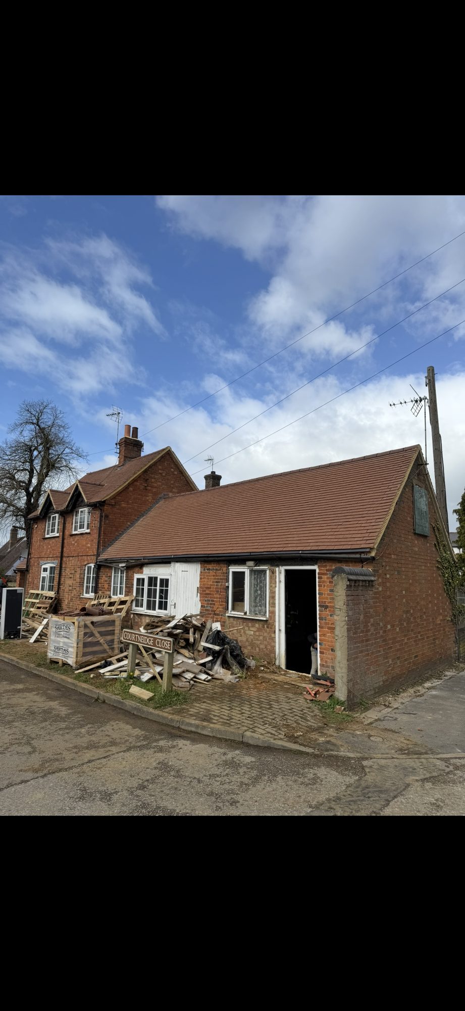 Newly tiled roof across the single-storey brick building, finished with matching ridge tiles and black guttering