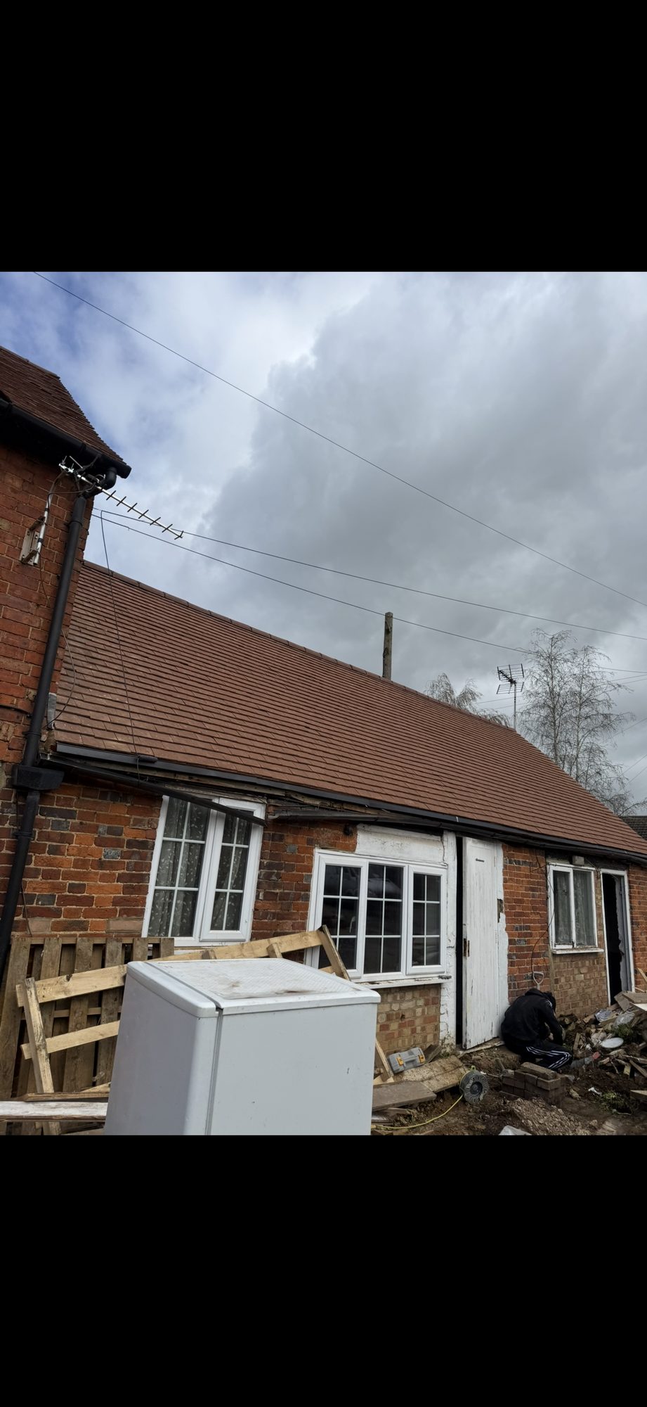 New roof tiles laid across the full length of the single-storey brick building with black guttering below