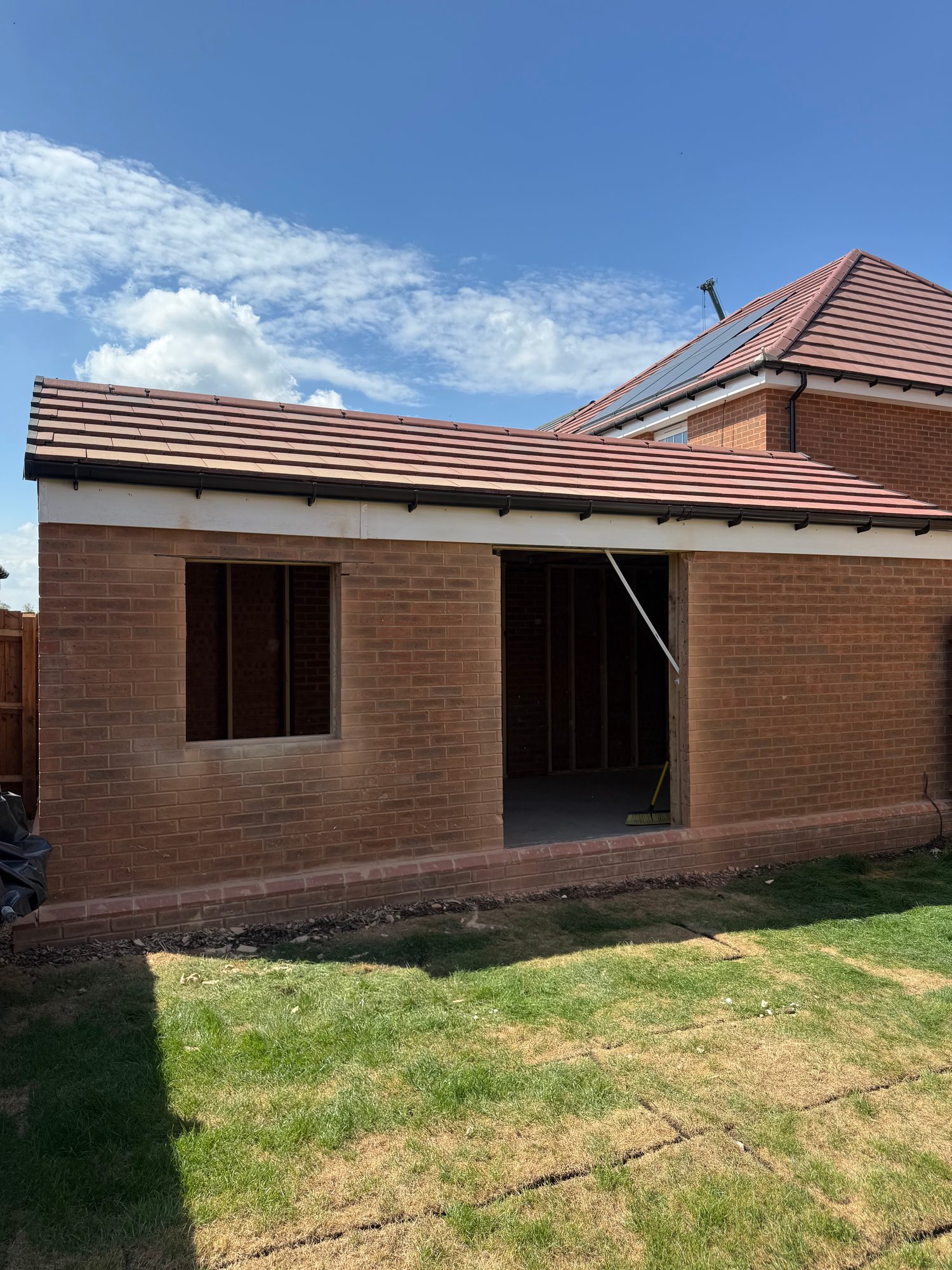 Side elevation during construction with new window and doorway openings formed in the brick wall
