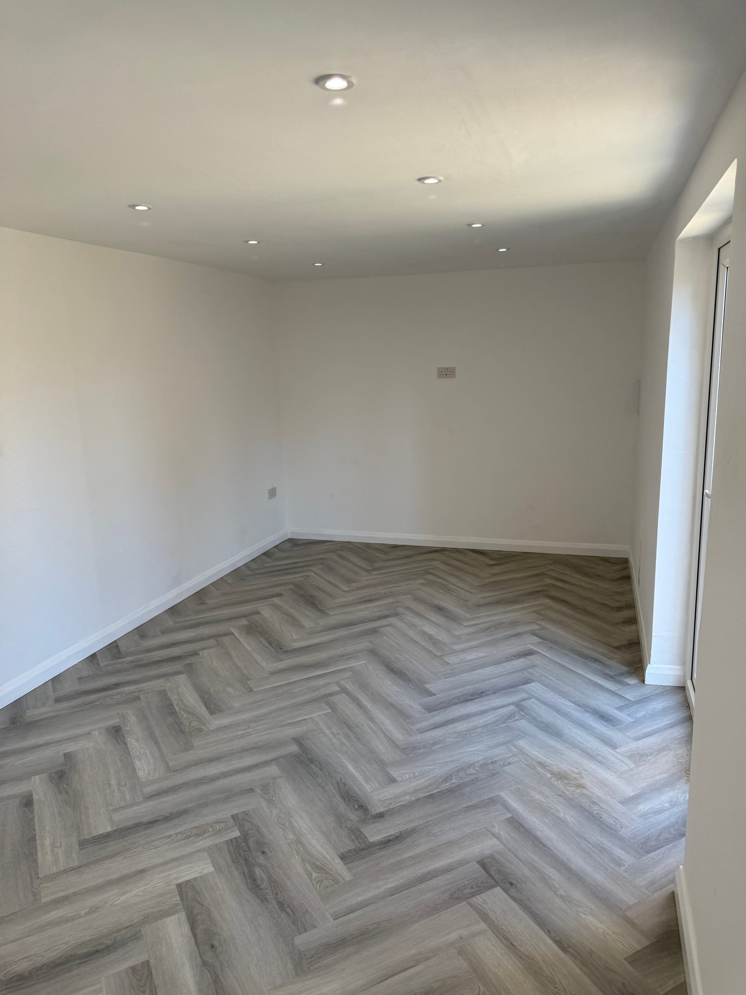 Finished interior showing grey herringbone flooring, recessed ceiling lighting and completed electrical fittings