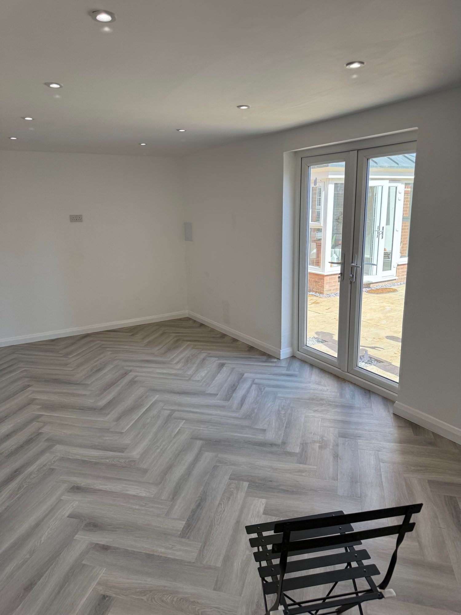 Finished room with herringbone flooring, recessed lighting and closed glazed double doors