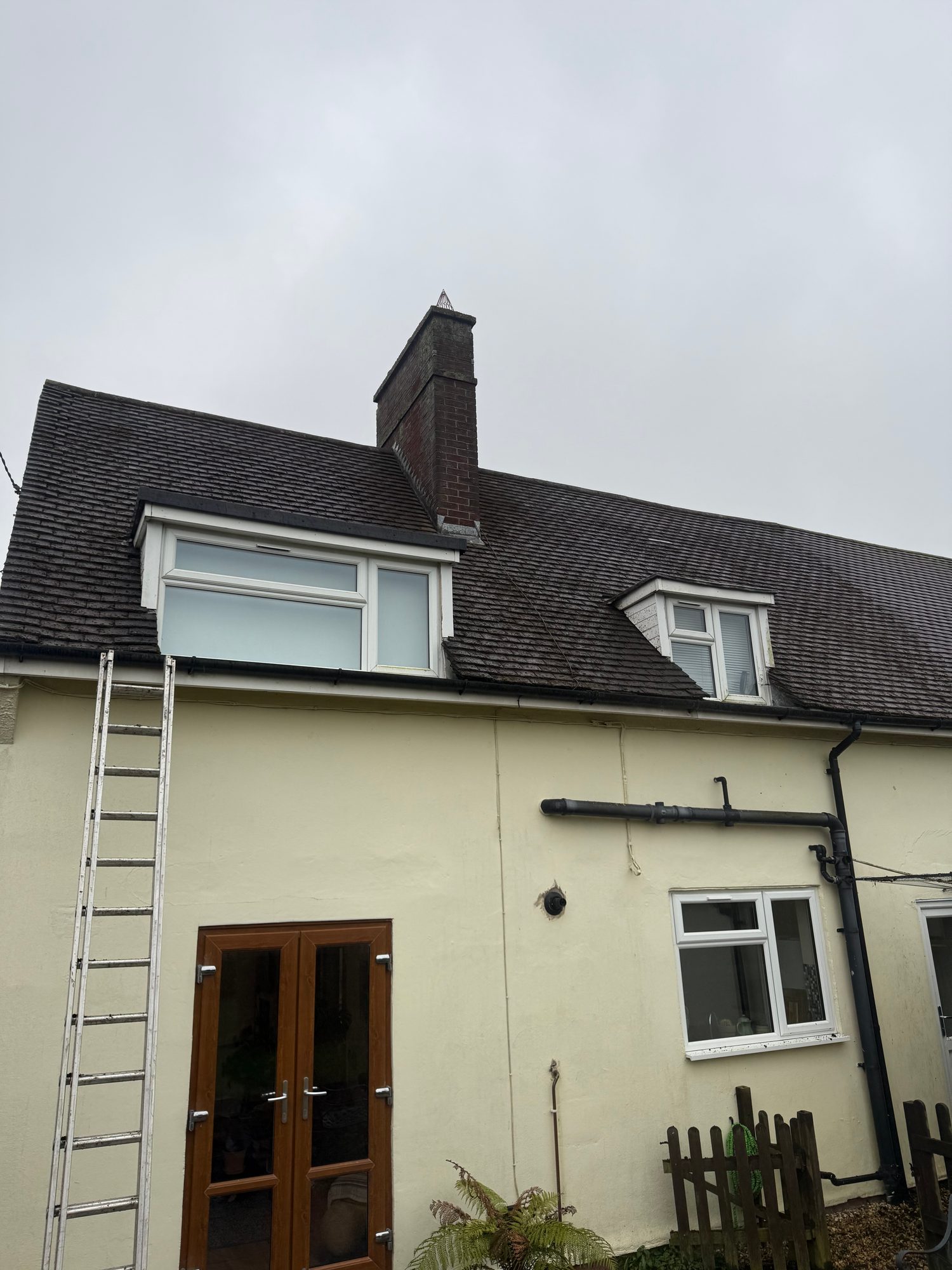 Clean roof tiles around the chimney and dormer windows following moss removal